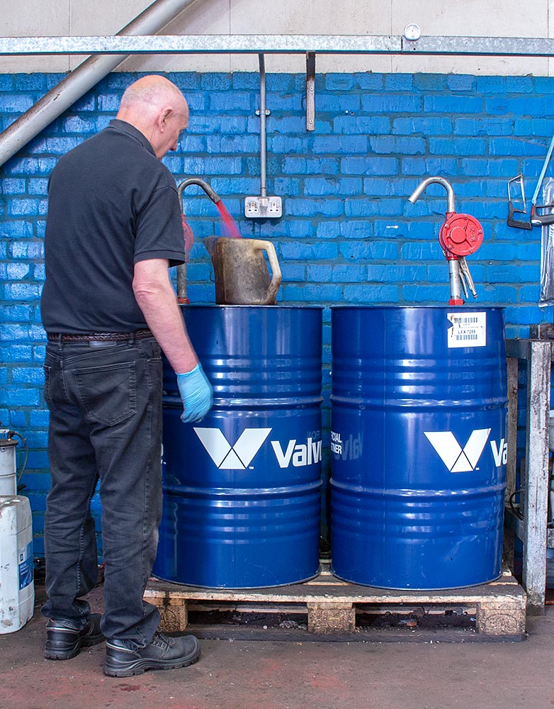 Mechanic dispensing brake fluid from drum